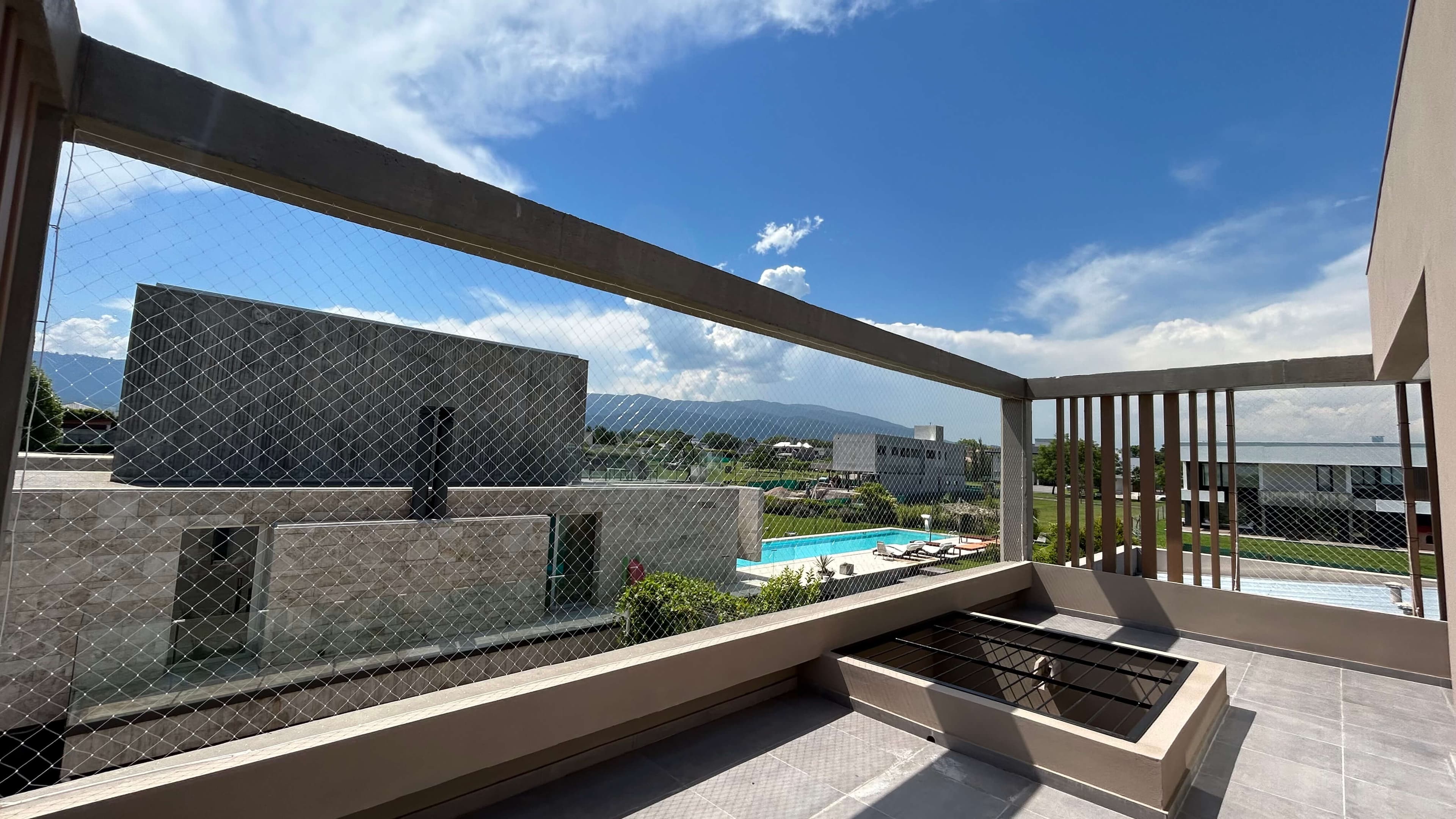 Balcón moderno con red de seguridad EQUIPESCA y vista a piscina y montañas